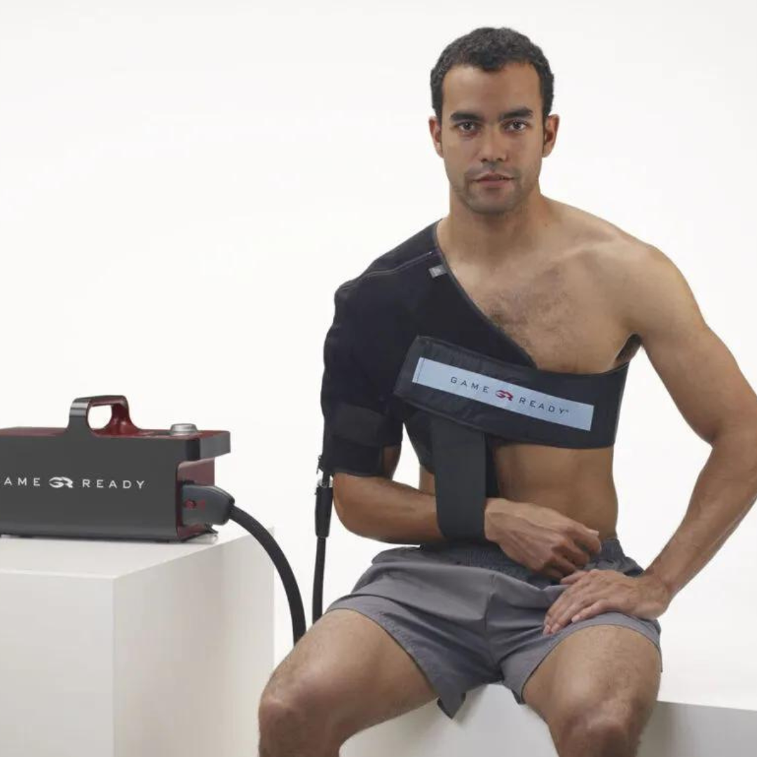 Uomo con fascia Game Ready applicata alla spalla, collegata al dispositivo per crioterapia e compressione attiva

